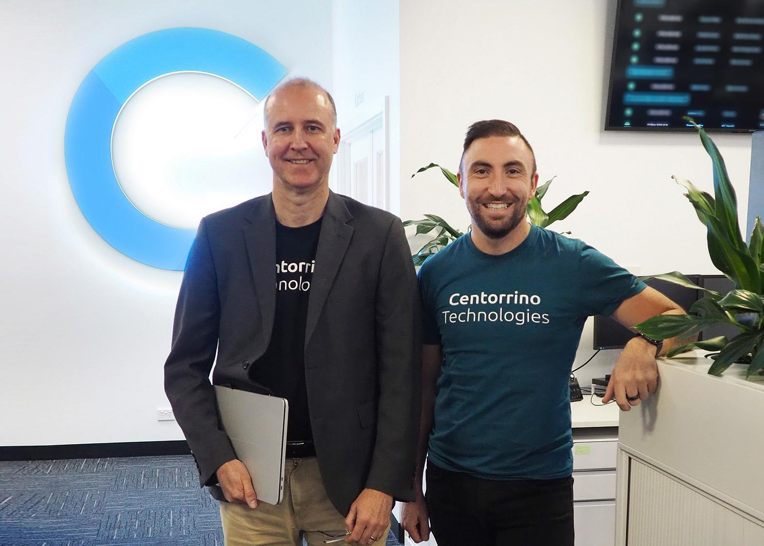 Steve Melville, former DQA CEO, and Adam Centorrino, CT's CEO smiling standing side by side in the CT office, wearing CT t-shirts.