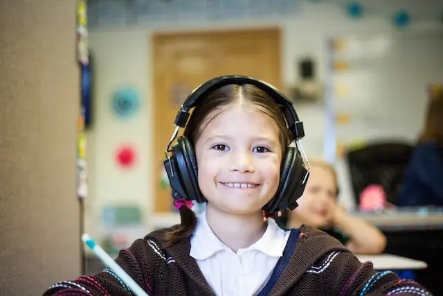 A young student wearing headphones and smiling