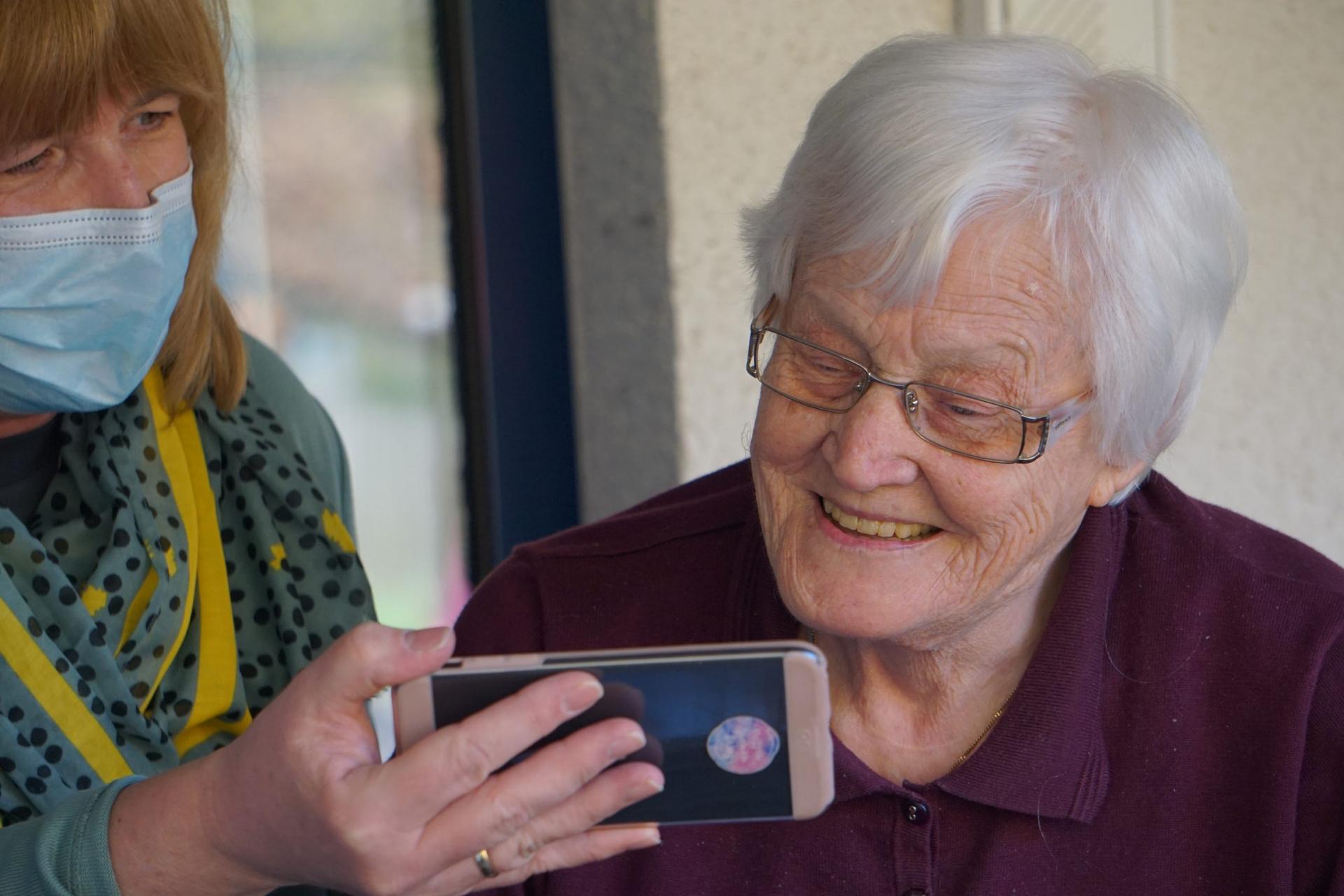 An image of an aged care nurse helping a resident use a smartphone